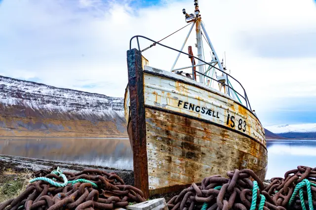 The rusting wreck of the fishing boat Fengsaell on a Westfjords shore with mooring chains, Iceland