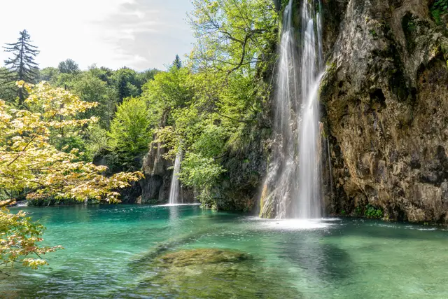 A waterfall tumbling into a turquoise pool at Plitvice Lakes, Croatia.